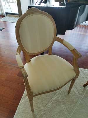 White wooden arm chair next to a piano